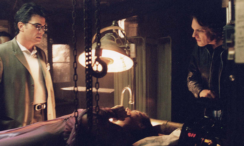 (L to R) Peter Gallagher, Famke Janssen and director William Malone on the creepy set of HOUSE ON HAUNTED HILL.